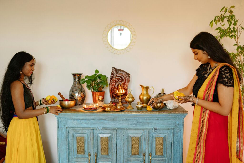 Two Indian women engaged in a sacred Diwali ritual at home, surrounded by traditional decor.